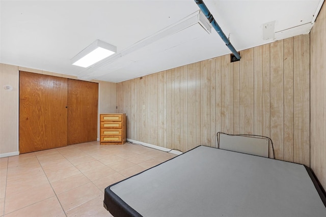 unfurnished bedroom featuring wooden walls, tile patterned floors, and a closet