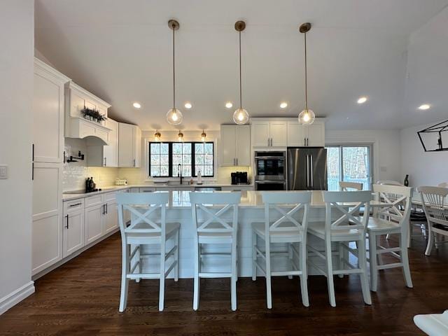 kitchen with pendant lighting, a center island, white cabinets, decorative backsplash, and appliances with stainless steel finishes