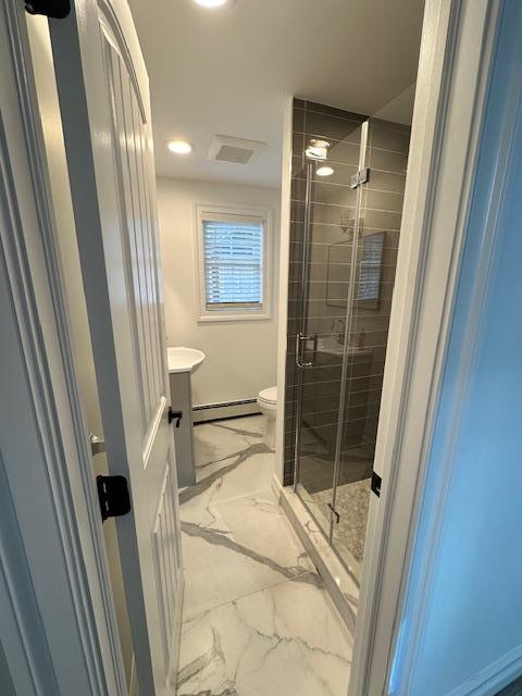 bathroom featuring baseboard heating, a shower with door, vanity, and toilet