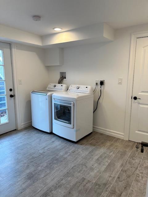 laundry area featuring washer and clothes dryer and light hardwood / wood-style flooring