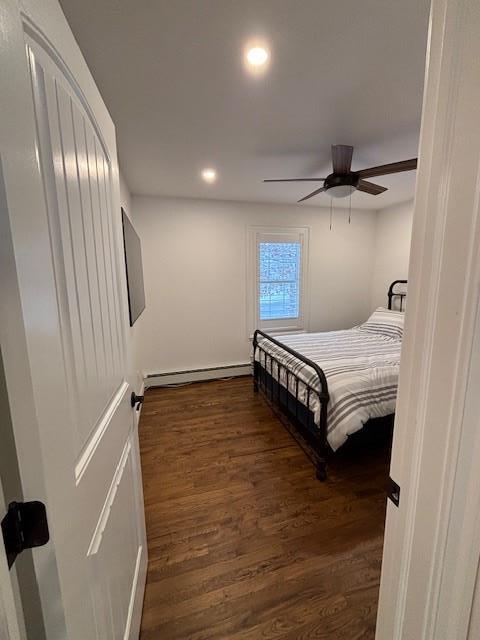 bedroom featuring ceiling fan, dark hardwood / wood-style floors, and a baseboard radiator