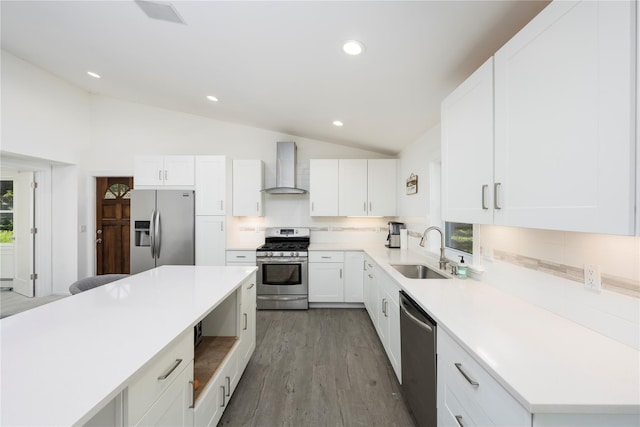 kitchen with white cabinetry, sink, wall chimney range hood, vaulted ceiling, and appliances with stainless steel finishes