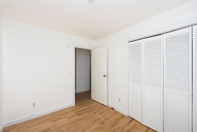 unfurnished bedroom with light wood-type flooring and a closet