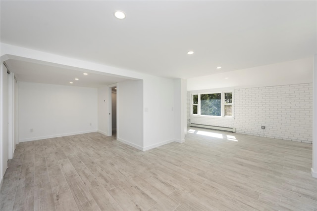 basement with light wood-type flooring, brick wall, and a baseboard radiator