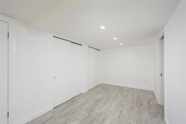 unfurnished bedroom with multiple closets and light hardwood / wood-style flooring