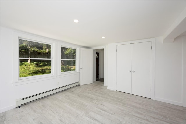 unfurnished bedroom featuring a closet, light hardwood / wood-style flooring, and a baseboard radiator