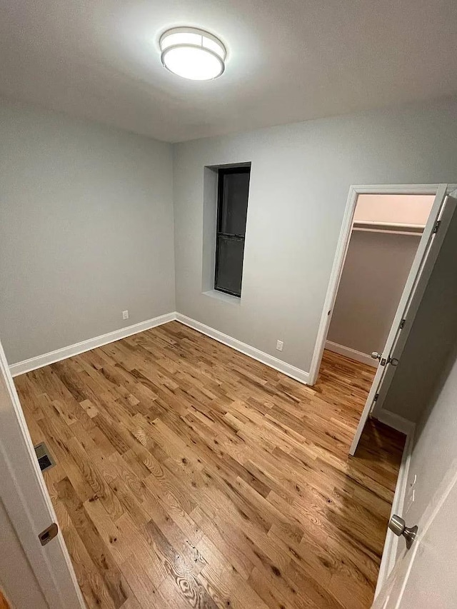 unfurnished bedroom featuring a walk in closet, a closet, and light wood-type flooring