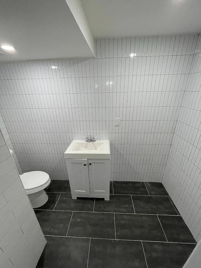 bathroom featuring tile patterned floors, vanity, tile walls, and toilet