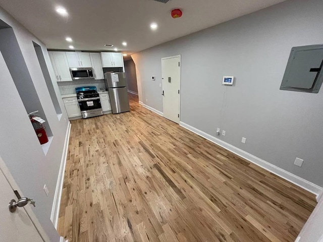 kitchen featuring decorative backsplash, light wood-type flooring, stainless steel appliances, electric panel, and white cabinetry