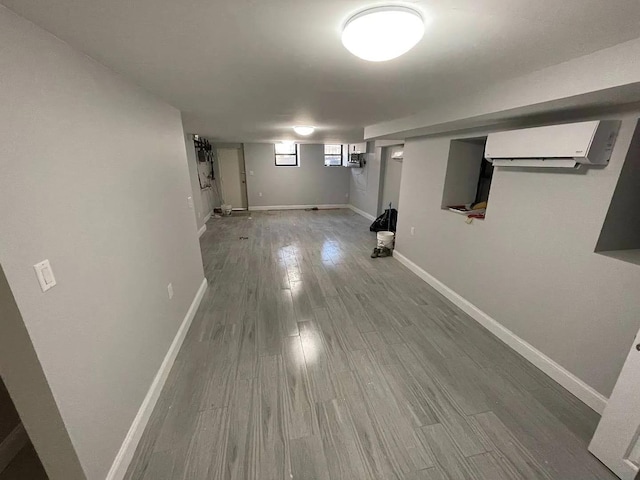 basement featuring a wall mounted AC and hardwood / wood-style flooring