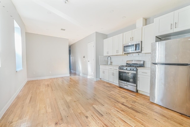 kitchen with white cabinetry, sink, decorative backsplash, stainless steel appliances, and light wood-type flooring