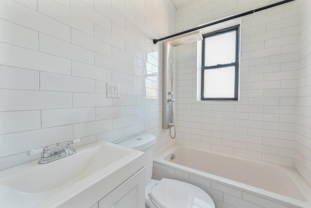 full bathroom with tiled shower / bath, tile walls, vanity, and toilet