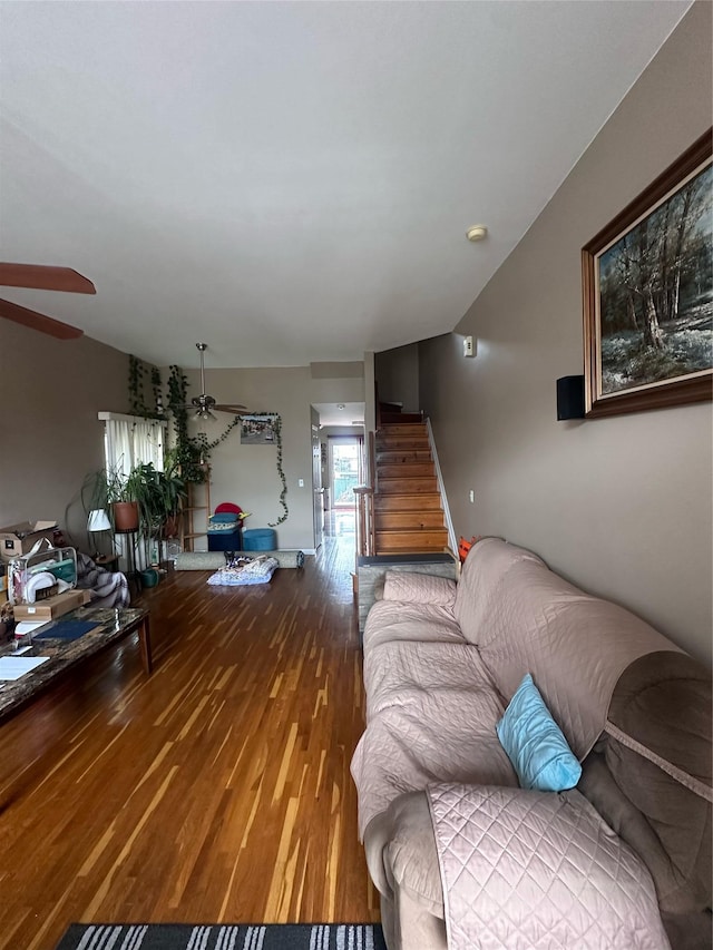 living room featuring vaulted ceiling, ceiling fan, stairway, and wood finished floors