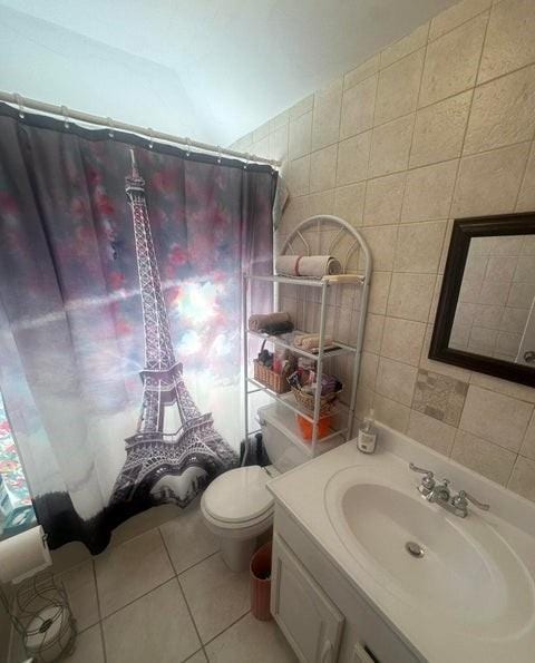 bathroom featuring tile patterned flooring, toilet, tile walls, and vanity