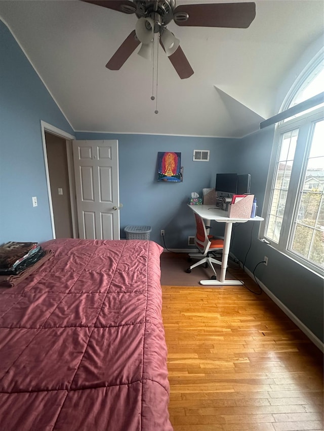 bedroom featuring lofted ceiling, visible vents, a ceiling fan, wood finished floors, and baseboards