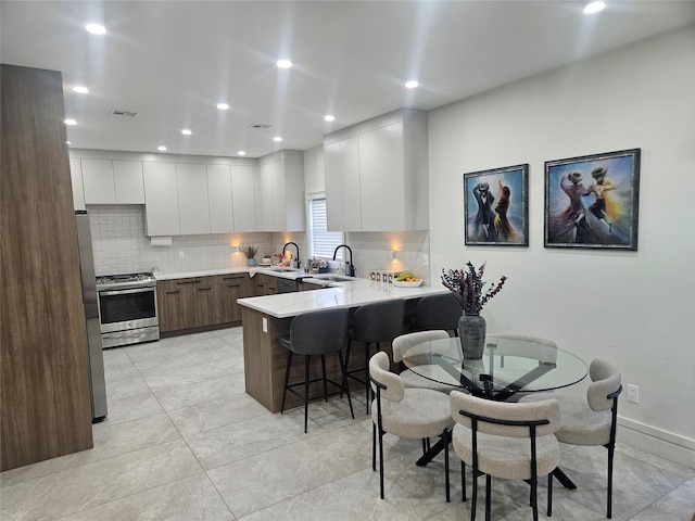 kitchen featuring sink, stainless steel appliances, a kitchen bar, decorative backsplash, and white cabinets