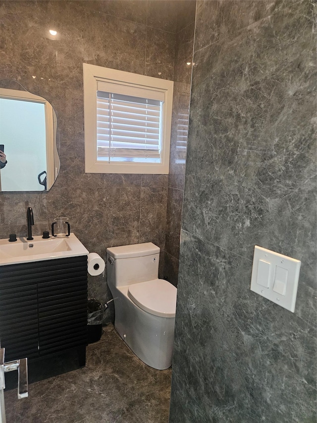 bathroom with vanity, toilet, and tile walls