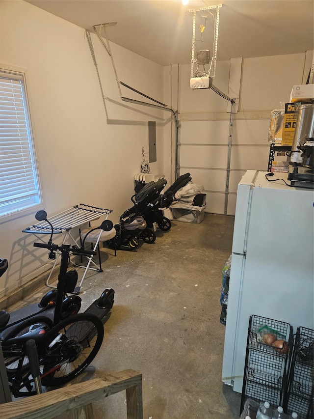 garage featuring white refrigerator, a garage door opener, and electric panel