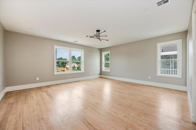 spare room with light hardwood / wood-style floors and a chandelier