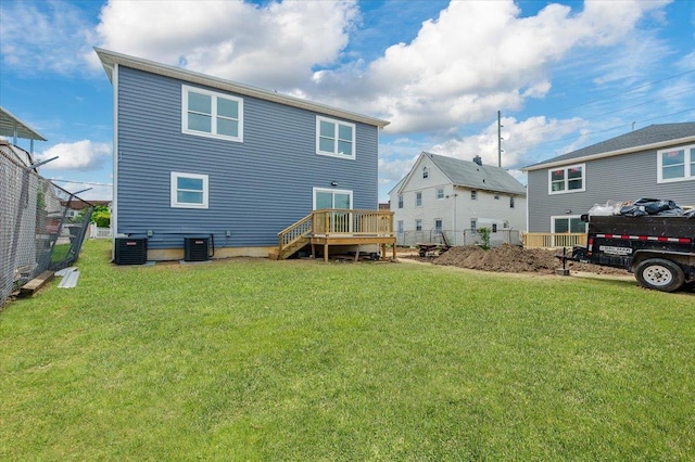 back of house with central AC, a deck, and a lawn