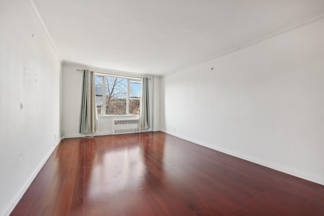 empty room featuring dark hardwood / wood-style flooring, radiator heating unit, and ornamental molding