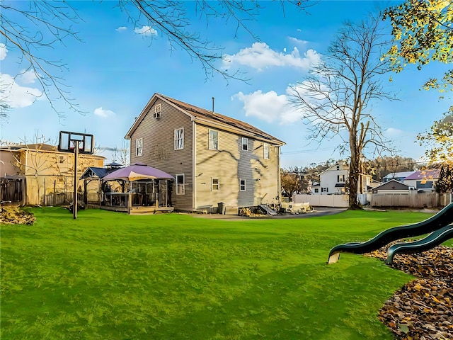 back of property with a gazebo, a playground, and a yard