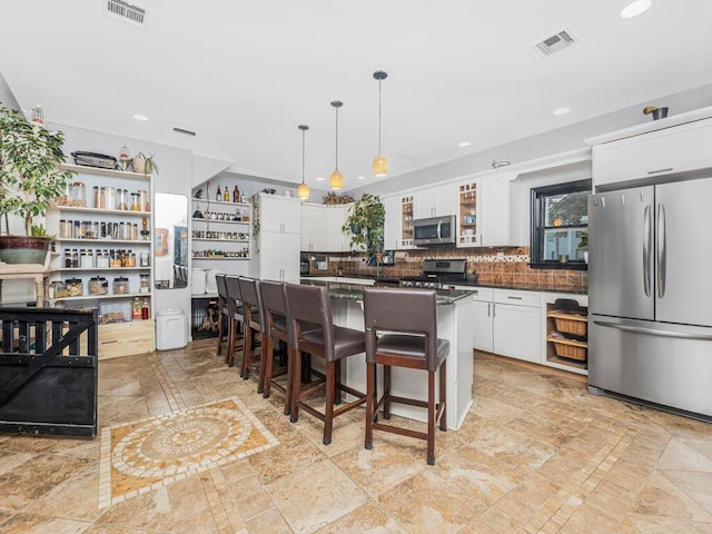 kitchen with pendant lighting, a center island, a kitchen breakfast bar, white cabinetry, and stainless steel appliances