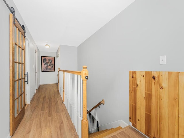 corridor featuring a barn door and light wood-type flooring