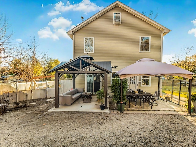 rear view of property with a gazebo, an outdoor living space, and a patio area