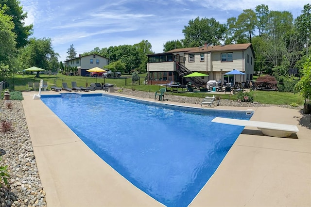 view of pool featuring a yard, a patio, a sunroom, and a diving board