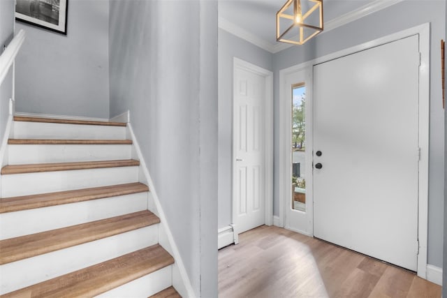 entryway with an inviting chandelier, light wood-type flooring, crown molding, and a baseboard heating unit