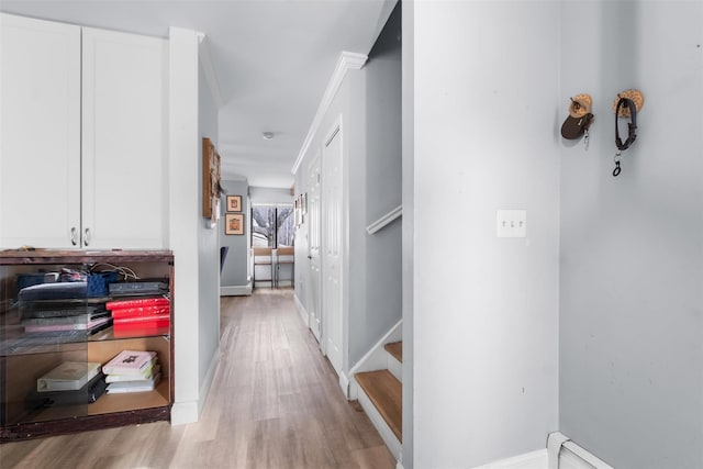 hall featuring a baseboard radiator, light hardwood / wood-style flooring, and ornamental molding