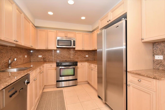 kitchen featuring sink, light stone counters, light tile patterned floors, stainless steel appliances, and decorative backsplash