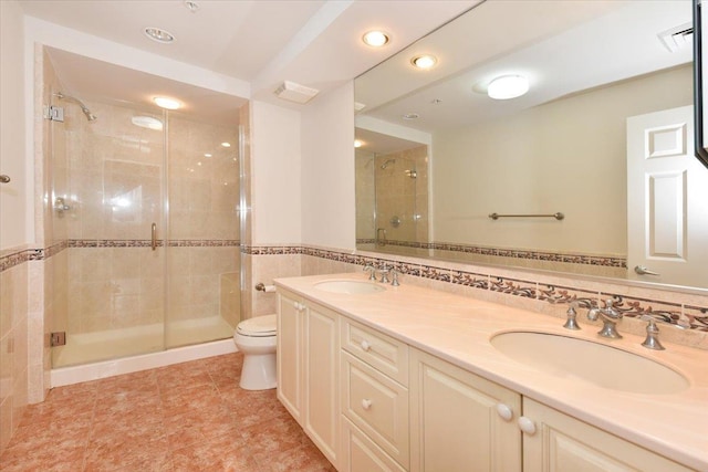 bathroom with an enclosed shower, vanity, tile walls, and toilet