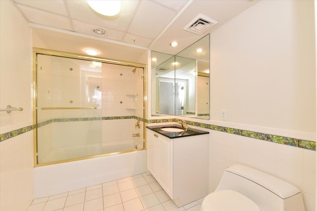 full bathroom featuring toilet, tile patterned flooring, combined bath / shower with glass door, and tile walls