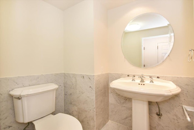 bathroom featuring tile walls and toilet