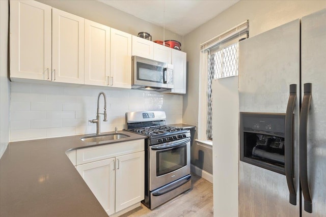 kitchen featuring decorative backsplash, appliances with stainless steel finishes, sink, light hardwood / wood-style flooring, and white cabinets