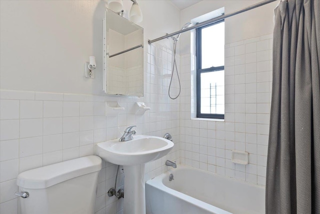 bathroom with toilet, shower / bathtub combination with curtain, and tile walls