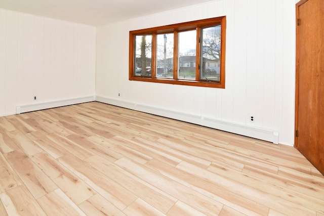 spare room with light hardwood / wood-style floors, wooden walls, and a baseboard radiator