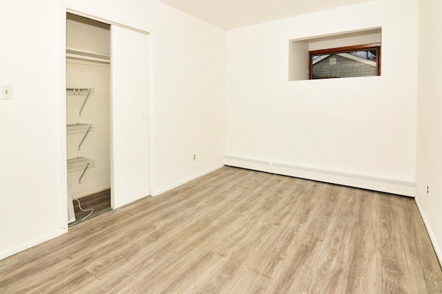 unfurnished bedroom featuring a baseboard radiator and light wood-type flooring