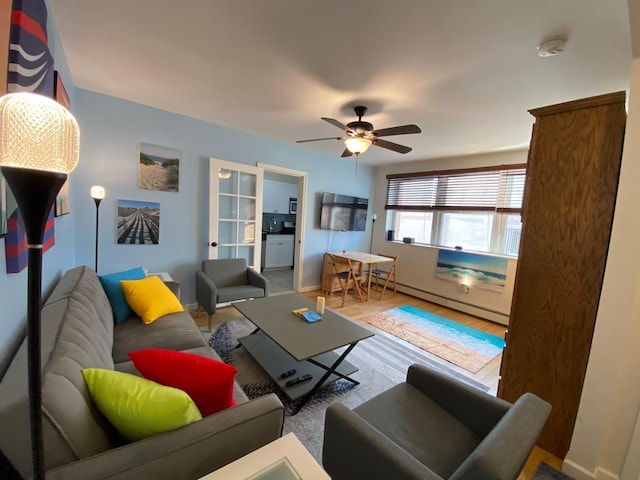 living room with wood-type flooring, ceiling fan, and a baseboard heating unit