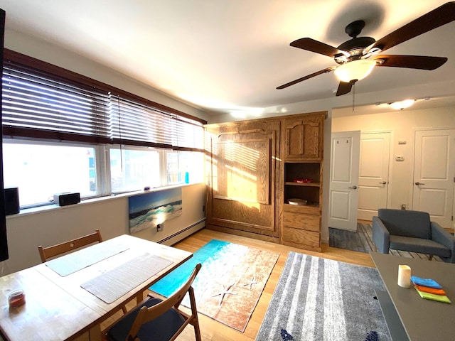 home office with ceiling fan, light hardwood / wood-style floors, and a baseboard radiator