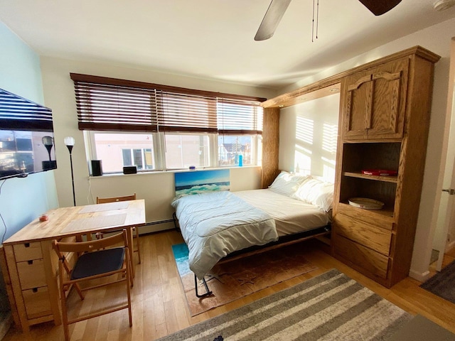 bedroom with ceiling fan, baseboard heating, and light hardwood / wood-style flooring