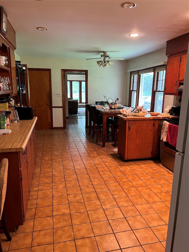 kitchen featuring kitchen peninsula, ceiling fan, light tile patterned flooring, and a wealth of natural light