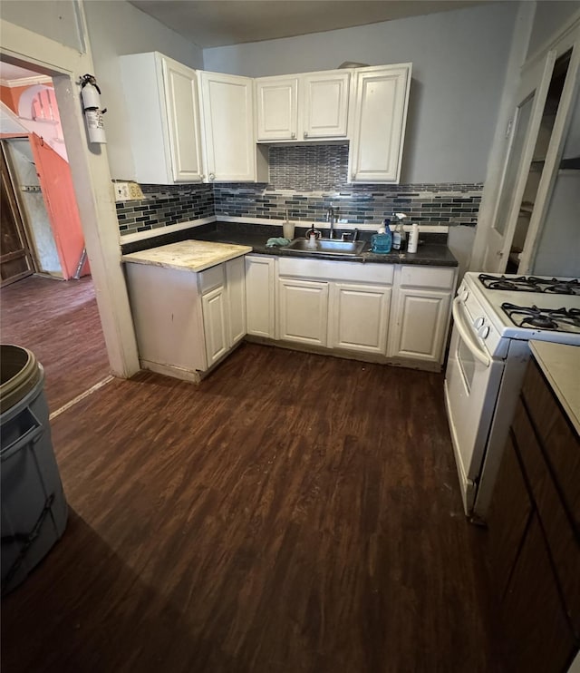 kitchen with backsplash, dark wood-type flooring, white range with gas stovetop, sink, and white cabinetry