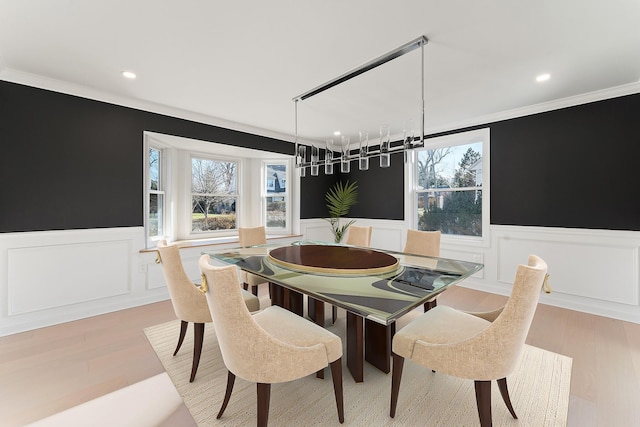 dining area with ornamental molding and light hardwood / wood-style flooring