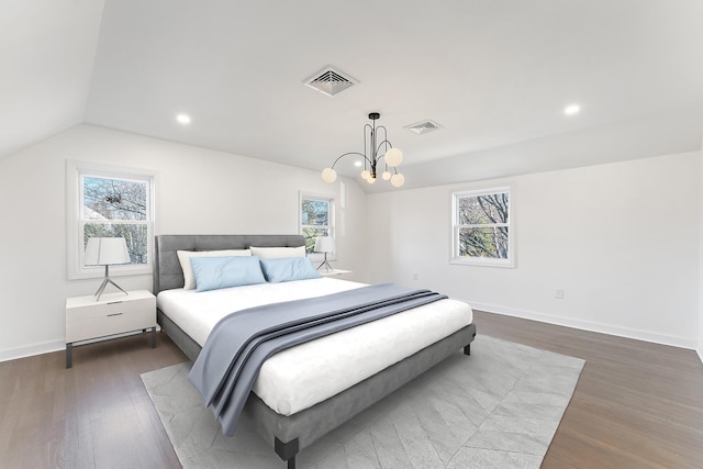 bedroom featuring dark hardwood / wood-style floors, lofted ceiling, multiple windows, and a chandelier