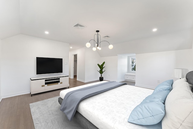 bedroom with hardwood / wood-style floors, a chandelier, and lofted ceiling