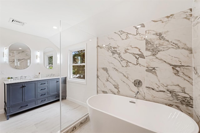 bathroom featuring vanity, a bath, and lofted ceiling