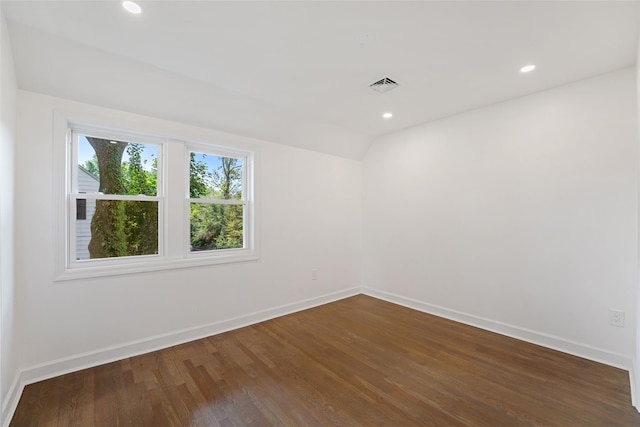 unfurnished room with vaulted ceiling and dark wood-type flooring